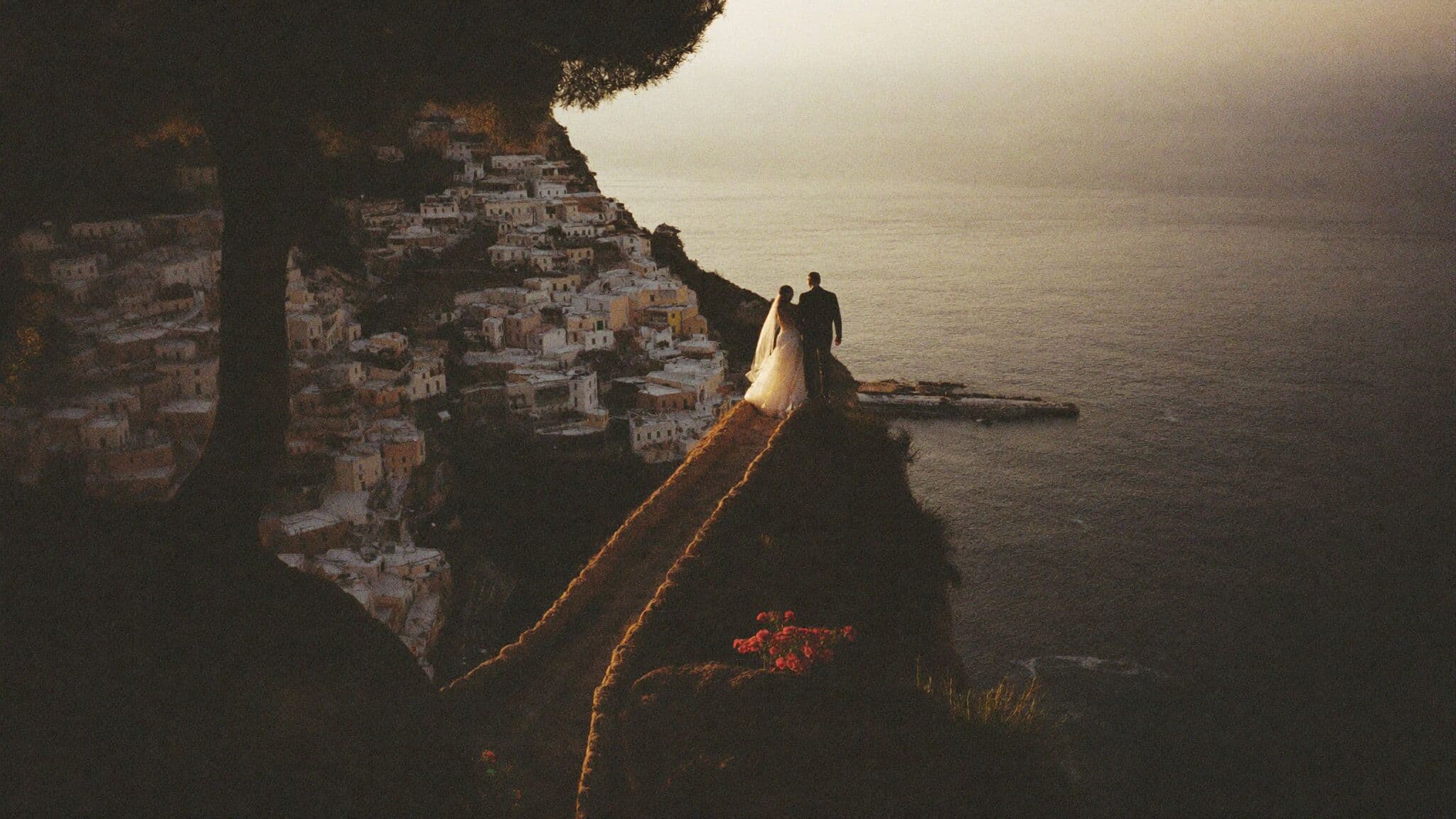 Couple embracing above the stacked pastel houses of Positano during their Amalfi Coast elopement