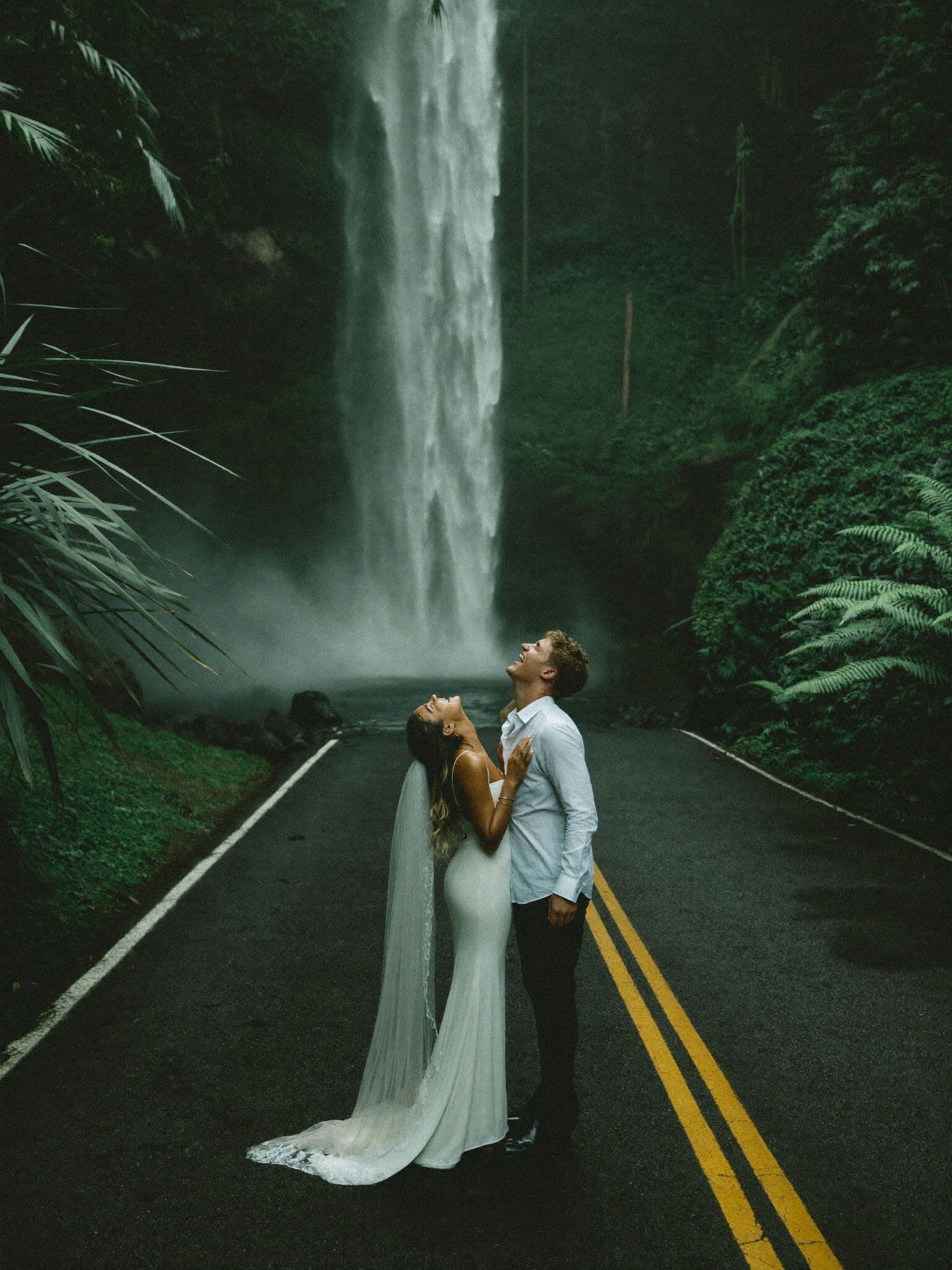 Couple standing beneath a jungle waterfall on the Road to Hana during their Hawaii elopement