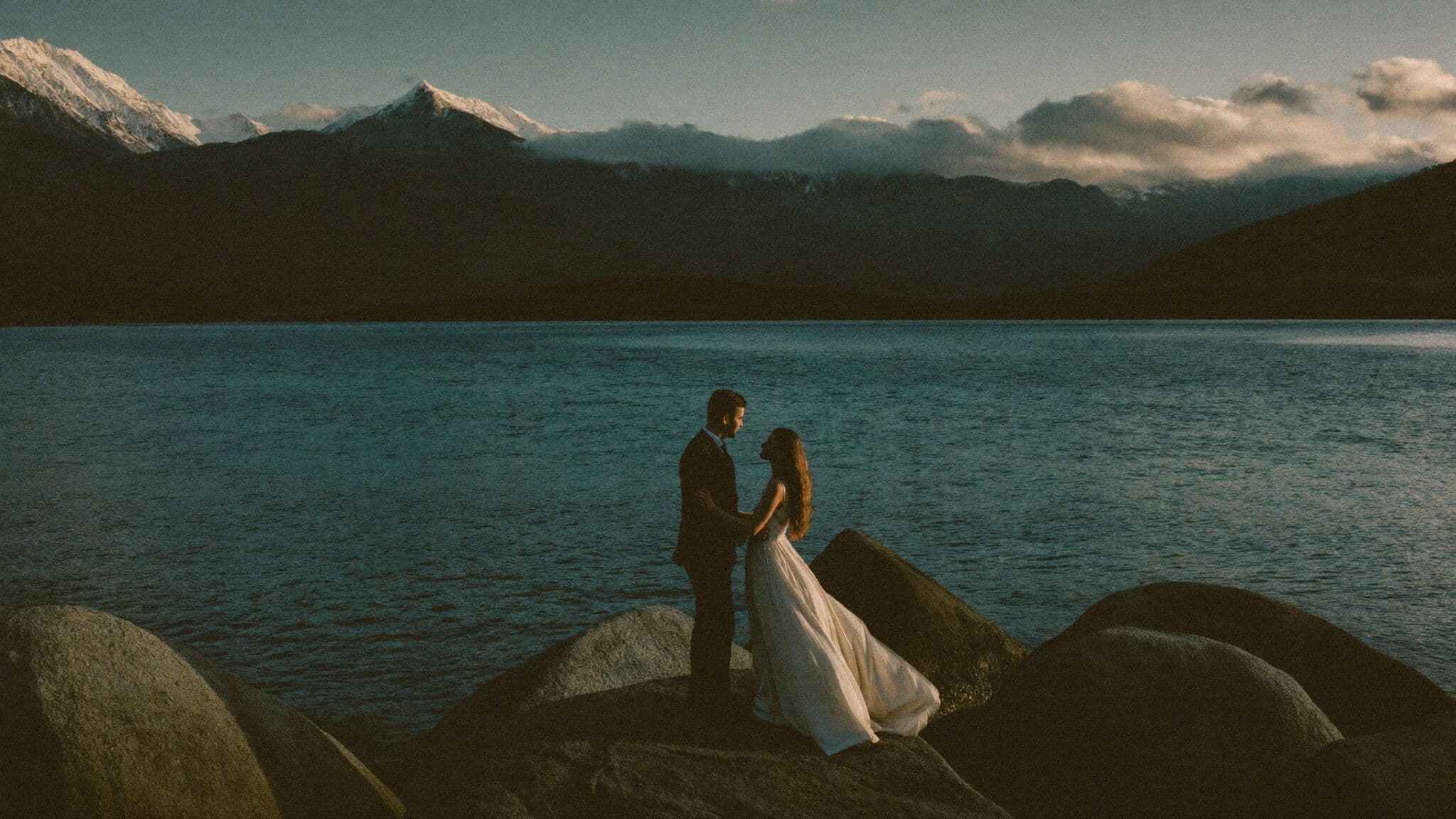 Couple standing among granite boulders on the Lake Tahoe shoreline during their elopement