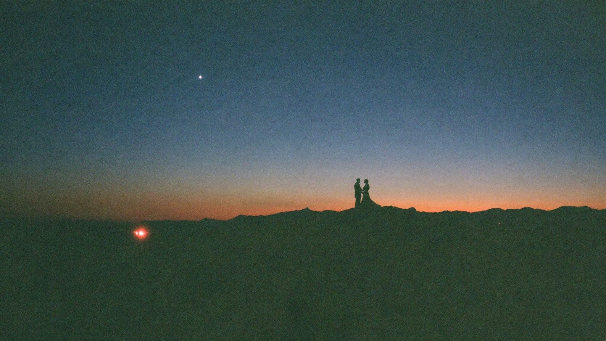 Couple silhouetted on a mountain ridge at blue hour during their adventure elopement
