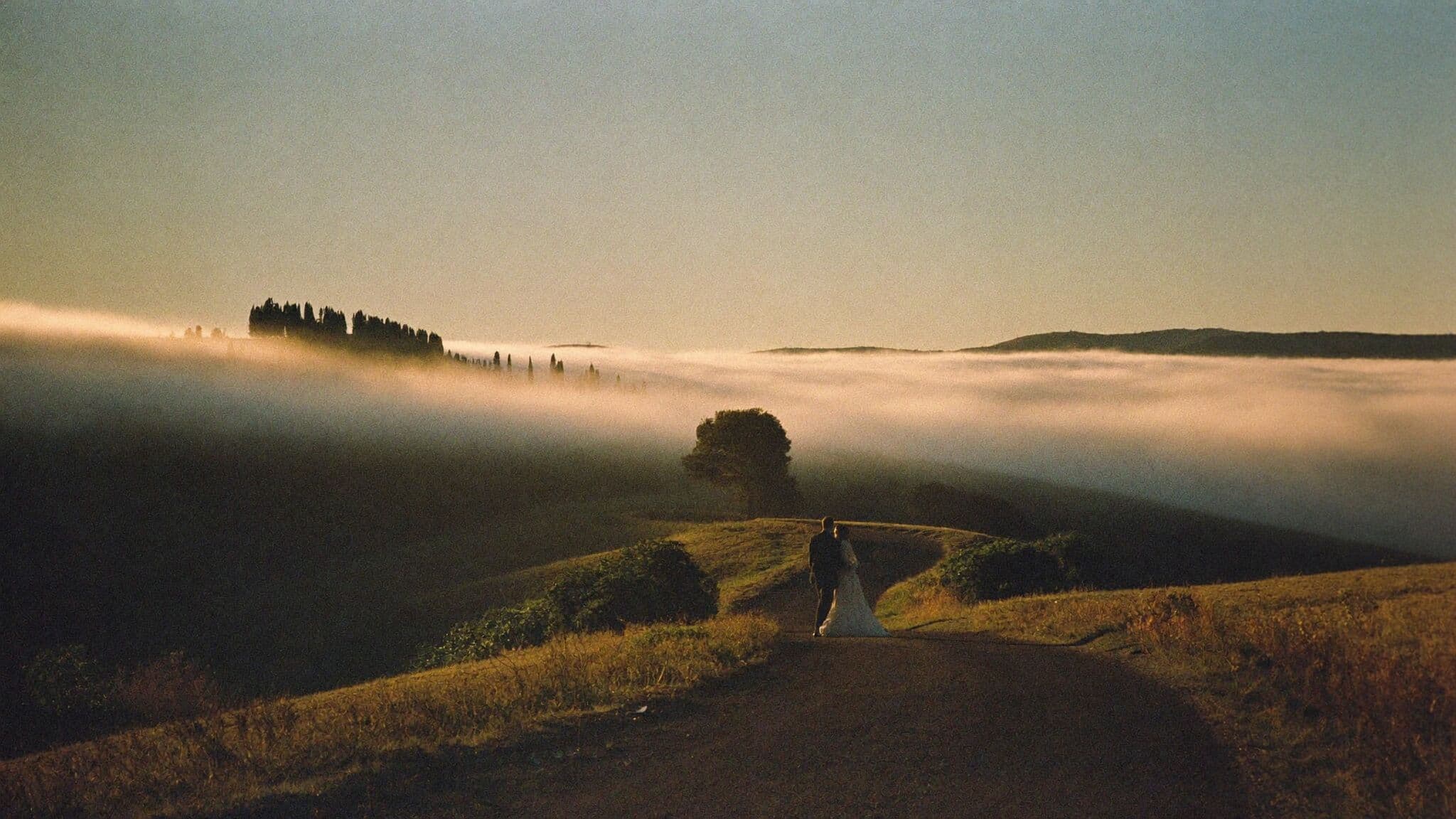 Bride and groom above dawn fog in the Val d'Orcia during their Tuscany elopement